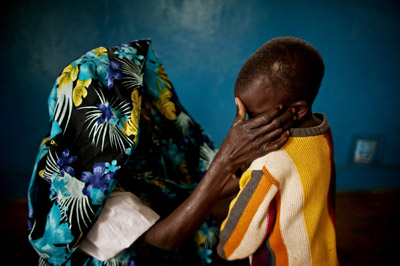 A survivor of the Fizi attacks sits with her son. The child suffered a head injury when soldiers threw him to the ground before raping his mother (AP)